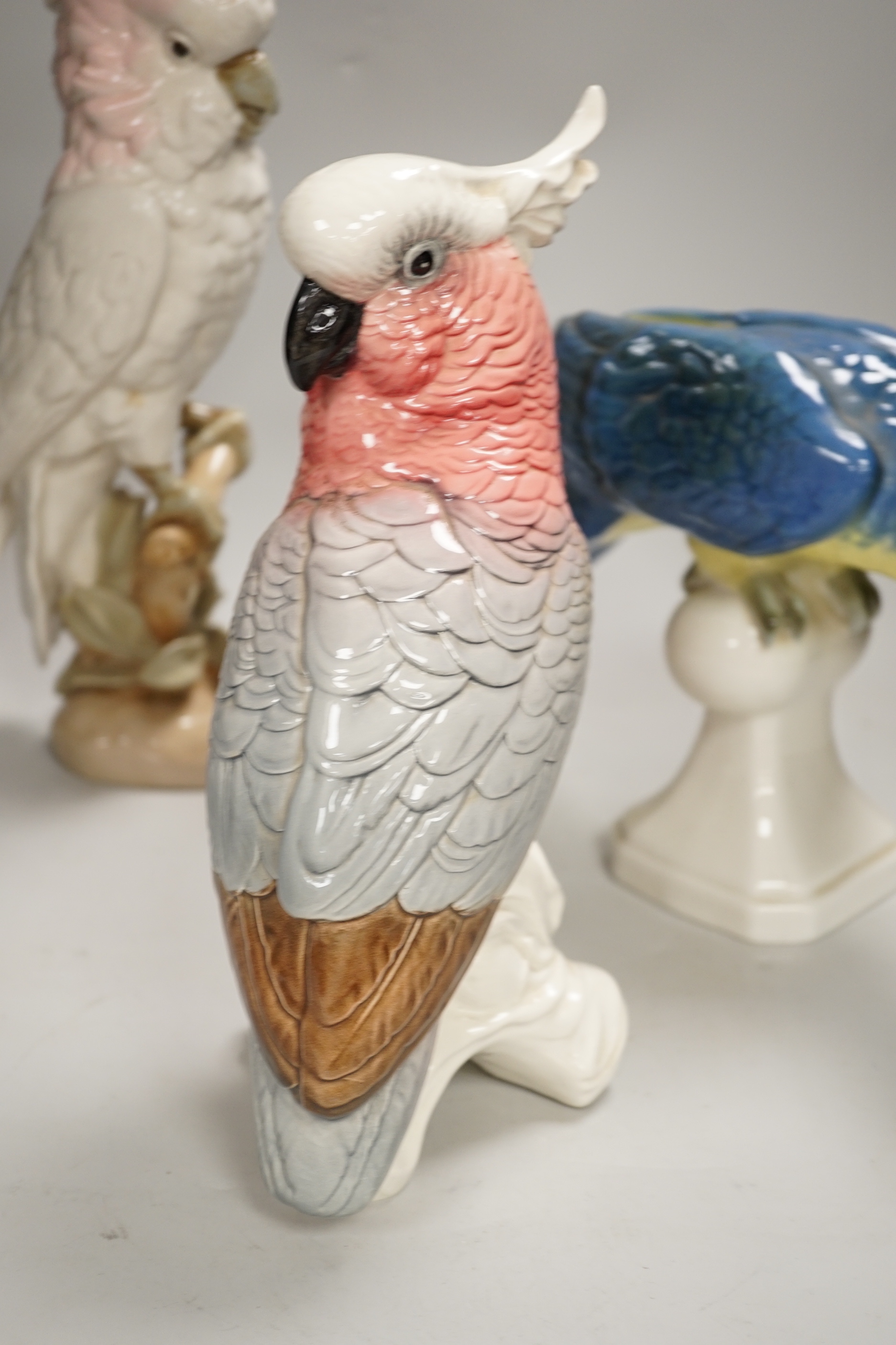 Two Royal Dux parrots and a Beswick parrot, the largest 40cm high